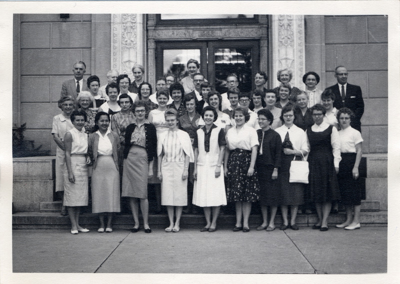 Library staff are gathered in front of the east entrance to the library for a group photograph. Row 1 (left to right) Mrs. Severa Vandergaast, Mrs. Sidney Chang, Karen Huisman, Cheryll Rankin, Gayle Thorson, Sonia Leistad, Sharon Snelling, Mrs. Mary Lou Wiebe, Mildred Danielson, Mrs. Helen Lentner. Row 2--Miss Grace Oberheim, Miss Frances Warner, Miss Margaret Orr, Mrs. Judy Madsen, Miss Janette Buck, Mrs. Caroline Gill, Mrs. Sue Hanson, Mrs. Eugenia Harris, Mrs. Mildred McCone, Sharon Stolte. Row 3--Mrs. Donna Hellinga, Mrs. Phyllis Murrell, Mrs. Roxanne Murray, Mrs. Tonie Whitman, Mrs. Sandra Gay, Mrs. Karee Henshaw. Row 4--Mrs. Jeanette Gilchrist, Mrs. Karen Heald, Mrs. Wanda Borchers, John Galejs, John McNee, Miss Elizabeth Windsor, Mrs. Dorothy Kehlenbeck, Mrs. Helen Zickefoose, Grant Hanson. Row 5--Robert W. Orr, Miss Evelyn Wimersberger, Mrs. Matyne Easton, Mrs. Eva Robbins, Miss E. Marjorie Smith.