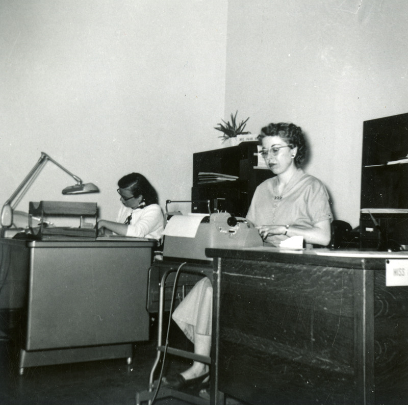 Magaret Mae Gross is typing, while Marilee Paink works at the next desk.