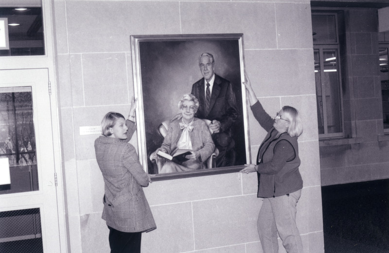 A formal portrait of W. Robert Parks and Ellen Sorge Parks is being hung on a wall located in the first floor atrium.