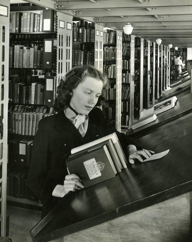 Lois Johnson Smith checks a request for books from the stacks. Book stacks are in the background.