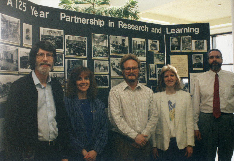 Library staff members (left to right): Dennis Wendall, Judy Hoffman, Tyler Walters, Renee Tesdall and Ed Goedeken are standing in front of a library display entitled, "A 125 year partnership in research and learning.".