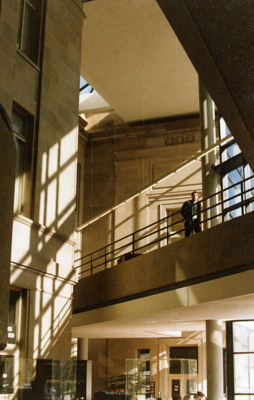 A student is walking along the second floor balcony that overlooks the open interior area of the new addition.