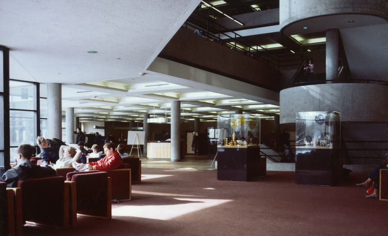 People are sitting in chairs located on the main floor of the 3rd edition. The spiral central staircase is on one side of the picture and the circulation service area is in the background.