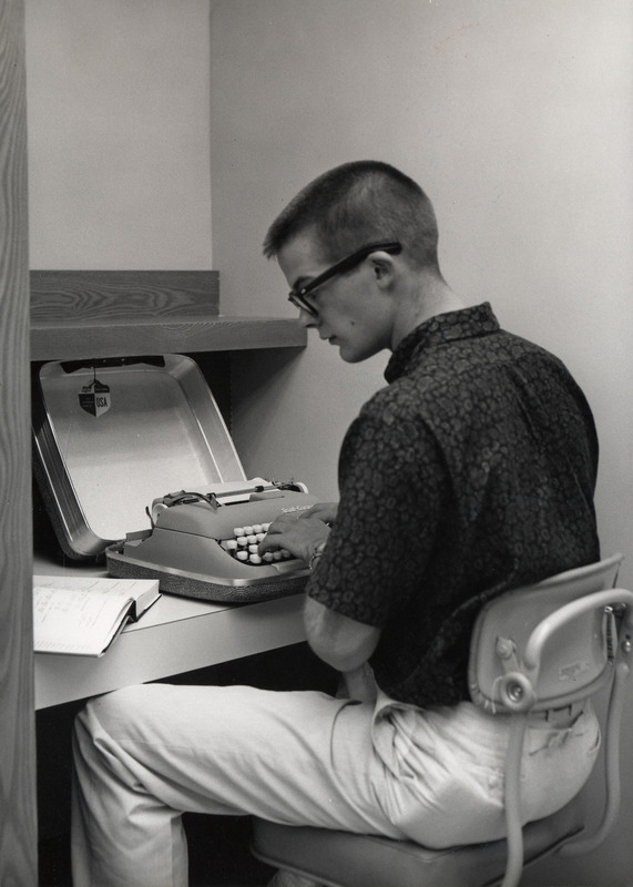 A male student uses a typewriter in the Typing Room of the newly opened 1st Addition.