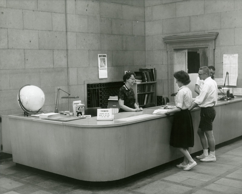 Head reference librarian, Elizabeth Windsor, helps students at the Information Desk, while reference librarian William Birdsall answers the telephone.