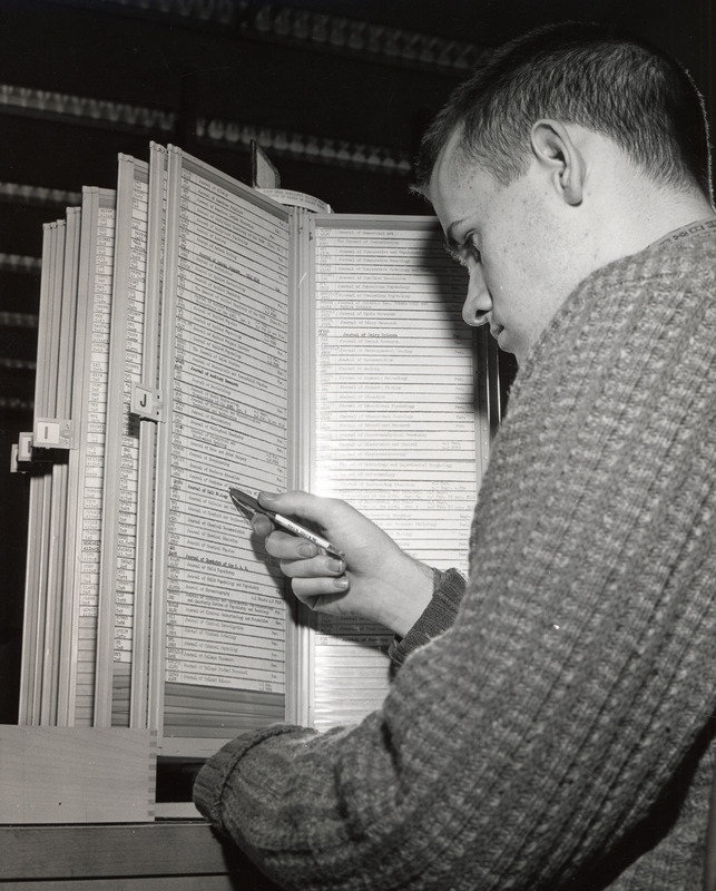 A male student consults the kardex for periodical location and holdings information.