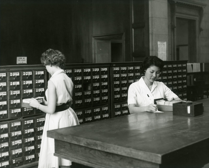 Alia Kotake and Patricia Fitzgerald work at the library card catalog.