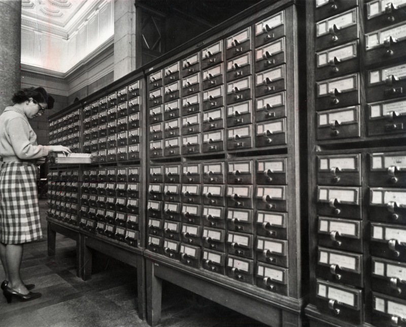 A woman in a checkered skirt peruses a drawer in the card catalog located in the upper rotunda lobby.