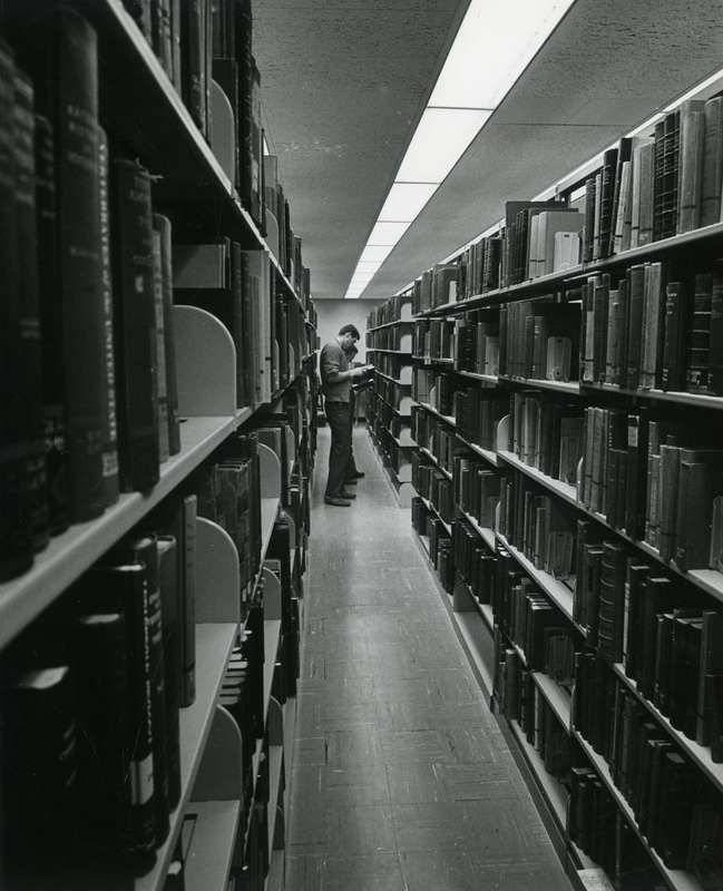 A couple of students examine books in the stacks.