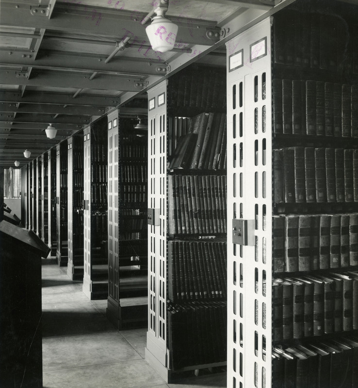 Library volumes are arranged on the shelves in the library tier. Book stands are positioned along the aisle on the left.