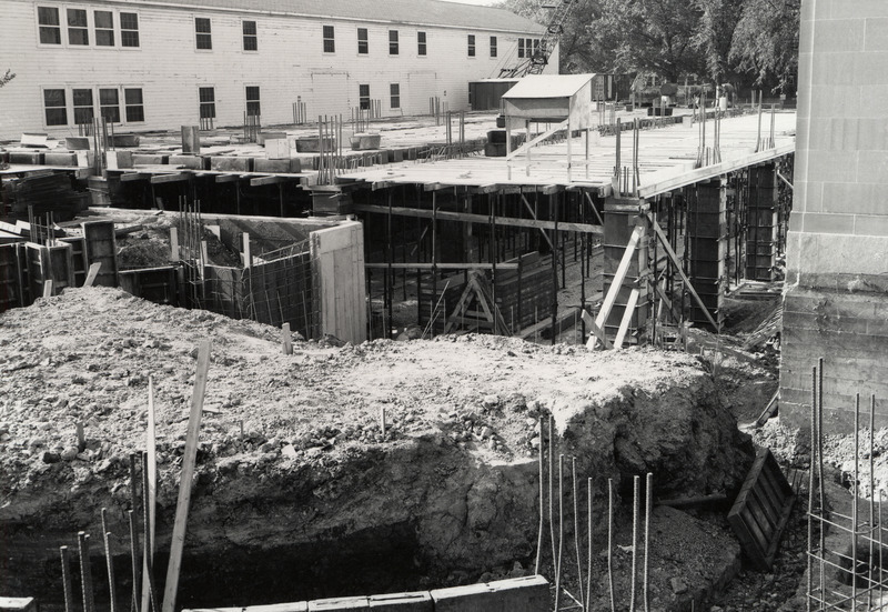 Viewed from above, some of the first floor framing for the 1st library addition is visible. The war surplus building, Number "N" is on the left.