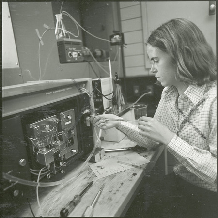 A researcher is working with a machine labeled analytical liquid chromatography. A screwdriver, scissors and other tools are on the workbench. This photograph was featured in the Chemical Engineering Brochure for 1978.