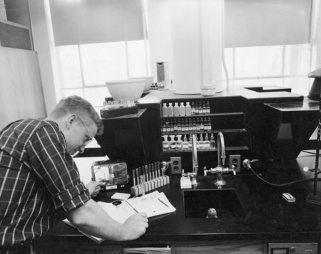 A student working in a newly designed laboratory for instruction in general chemistry employing semi-micro techniques. Test tubes and reagent bottles are arranged neatly at the work station.