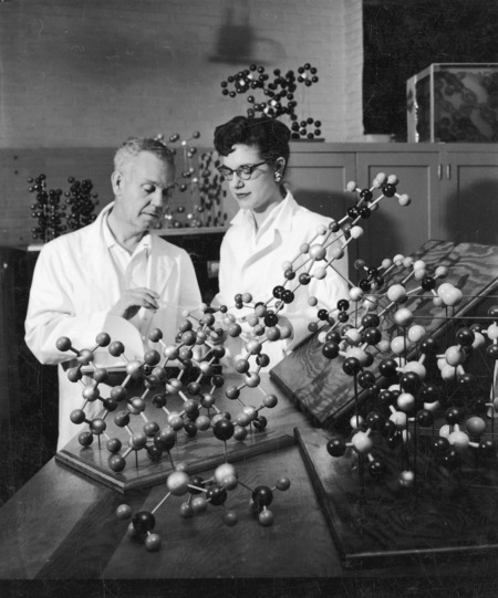 H. Frederick Hollenbeck and Frances Hiltrop working with models of complex crystals. In addition to a large model in the foreground there are models shelved behind them.