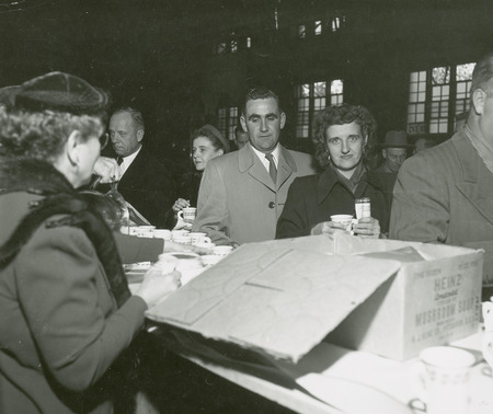 A group of individuals are going through a serving line for beverages at a Homecoming event.