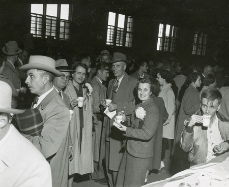 A group of individuals are enjoying refreshments and conversation at a Homecoming event.