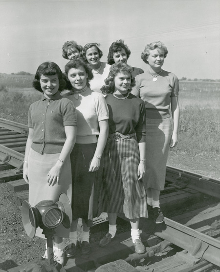 The 1950 homecoming queen candidates standing on the railroad tracks behind a signal light are front row (left to right): Rita Dunn (Queen), Sioux City; Claire Schubert, Maywood, IL; Betty Skyberg (Attendant), Canton, SD; back row (left to right) Marlene Sidney, Davenport; Pat Binder, Barrington, IL; Janet Green, Sac City; Ethel Pearce (Attendant), Mesa, AZ.
