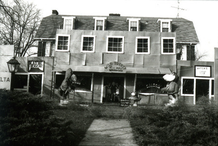 The Phi Gamma Delta house, Alpha Iota chapter, is transformed into the Wild Turkey Saloon for a Homecoming lawn display, with Cy and the Kansas University Jayhawk engaged in a Wild West shootout, 1977.