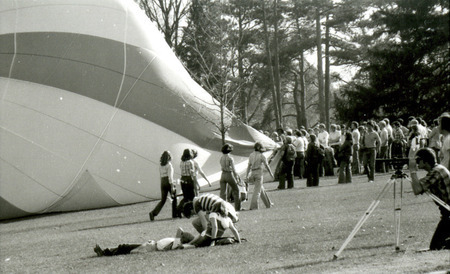 A crowd and a photographer watch a balloon being filled with hot air on Central Campus for Homecoming, 1978.