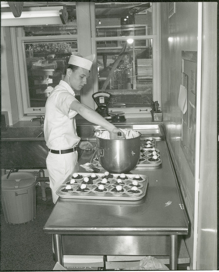 Making for the VEISHEA pies. A male student in the kitchen tops the cherry pies.