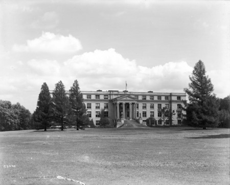 The front (west) facade of Agriculture Hall (Curtiss Hall) is framed by three large pine trees on the north and one on the south.