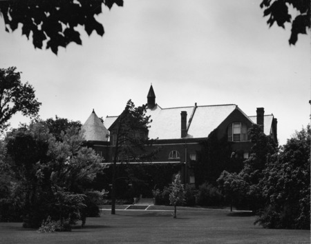 View of the front (east) side of Morrill Hall. Many bushes and trees are in the forefront of the photo.