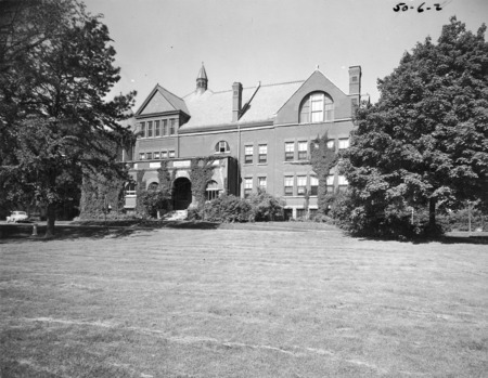 View of the front of Morrill Hall with trees flanking each side. Ivy is growing on the front of the building.