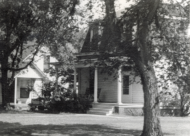 Photograph looking south-east at the Farm Boarding Club when the building was located at the corner of Beach and Wallace. Part of the Teamster’s Cottage #2 can be seen to the left (east side) of the Farm Boarding Club. Annotation: “Farm Boarding Cottage, 1957.”