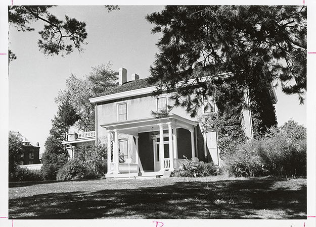 Photograph looking north-west at the front porch and south side of the Farm House. Part of Catt Hall can be seen in the background to the left (north-west) of the Farm House. Annotation: "Farm House."