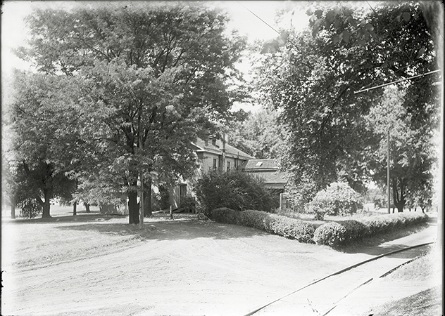 Photograph of the north-west corner of the Farm House with Dinkey tracks in the foreground. Annotation: “Horse barn redesigned in 1930 for Landscape Architecture.”