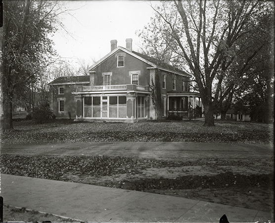 Photograph showing the south-west corner of the Farm House including both the west and south porches. The Creamery, First can be seen in the background to the right (west) of the Farm House. Annotation: “Farm House ca. 1911.”