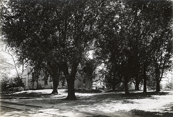 Photograph of Dinkey tracks as they run behind (north of) the Farm House. Annotation: “Farm House 1906. Motor track in foreground.”