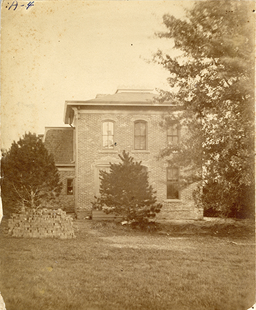 Photograph of Sloss House with a pile of bricks in the foreground.