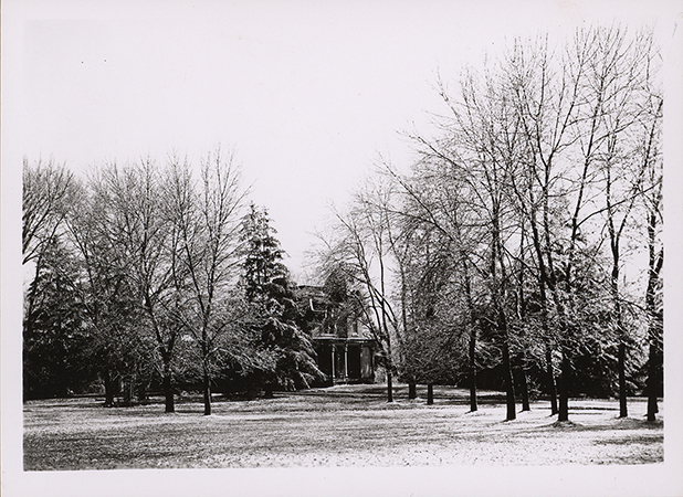 Photograph of South Hall on the Iowa State campus, showing the north and west elevations. The view is looking southeast. The building is partially obscured by a landscaped setting of leafless trees and open lawn with light snow on the ground. Annotation: "Music Hall (Old South Hall, built in 1869), located south of Campanile. Burned in 1912. South Hall."