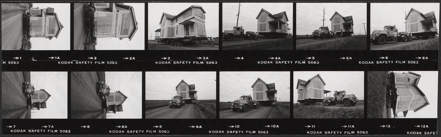 Contact sheet consisting of a strip of photographs documenting the relocation of Pope Cottage off the Iowa State campus. The images show a small wooden house being transported along a rural road on a trailer pulled by a truck, with sequential views capturing different stages of the move. Annotation: "Moving Pope Cottage off campus. 1981 (June 11). Neg #’s 030128–030129 (strip).''