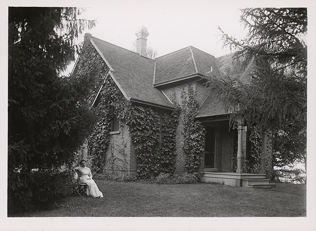 Photograph of Lillian Spray sitting outside the southwest corner of Osborn Cottage. Annotation: ''Mrs. Lillian Spray, housekeeper for Prof. Summers, sitting in front of the Osborn Cottage when the Summers family lived there. Around 1906.''