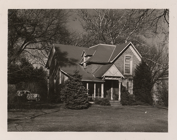 Photograph of the southwest corner of Osborn Cottage with a car parked facing the west side of the building.