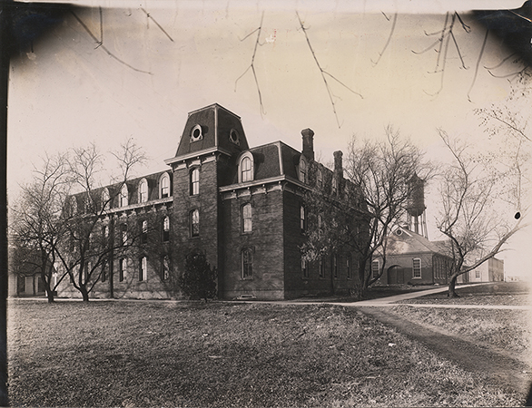 Photograph looking north-west at the southeast corner of the Laboratory of Mechanics. The Quarantine Hospital can be seen to the west (left) of the Laboratory and the Steam & Gas Lab, Marston Water Tower, and Building A can be seen to the north (right).