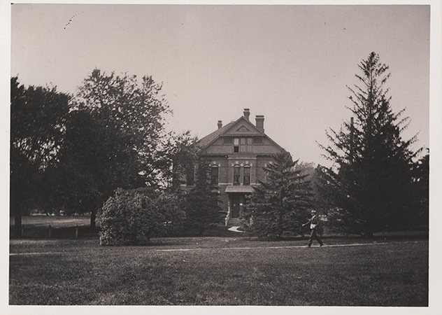 Photograph of a person walking in front of the English Office building.