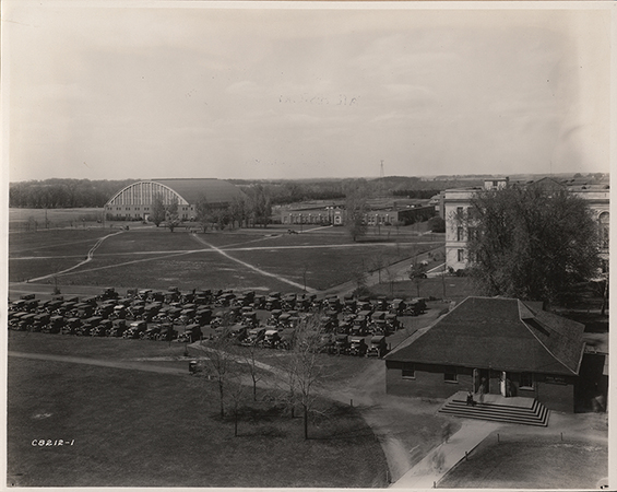 Photograph of cars parked west of the Hub when it was the Post Office. The Armory, Davidson Hall, and library can be seen in the north-west (background).