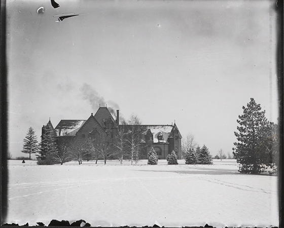 Photograph showing the south side of Margaret Hall with some snow on the roof and the ground covered with snow. Annotation: ''Dr. Spinney's collection.''