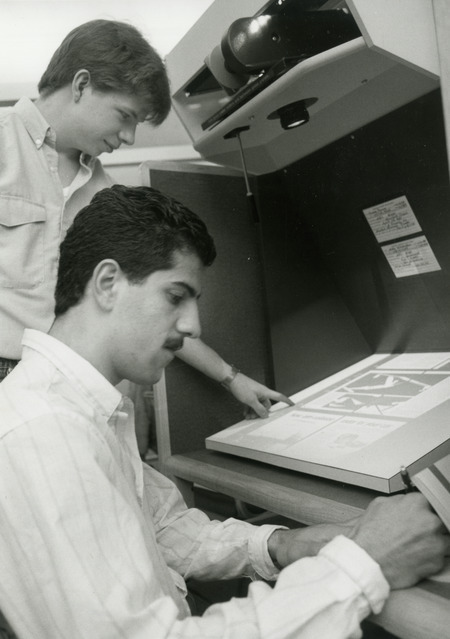 Two students are working with a projector microfilm machine.