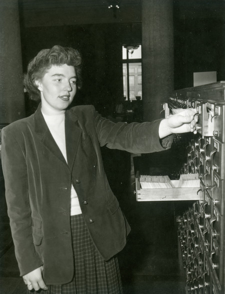 Instructor Mrs. Maralyn Welin is standing before a card catalog cabinet delivering a lecture in Library instruction.