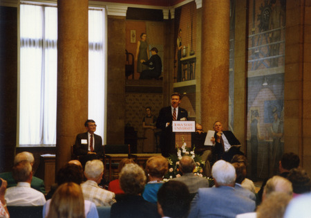 ISU President Martin Jischke is at the podium speaking at the dedication of the Presidential Portrait Gallery in the library's upper rotunda lobby, with former president Gordon Eaton sitting on the left.