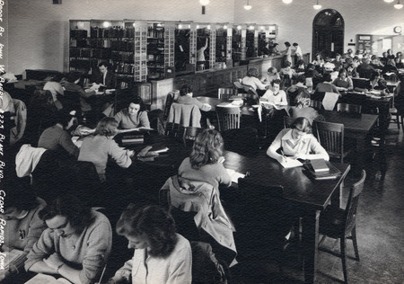 The reserve desk and shelves are visible behind tables of students in the Reserve Book Room (currently Room 198).