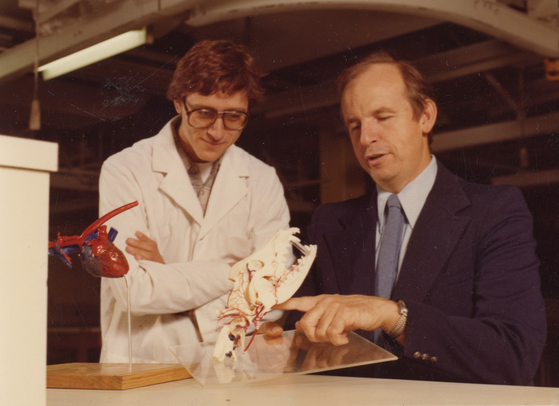 Photograph of Donald Adams with veterinary student Frank Loparco examine a dog skull and a canine heart fixed and injected to show vessels and blood flow