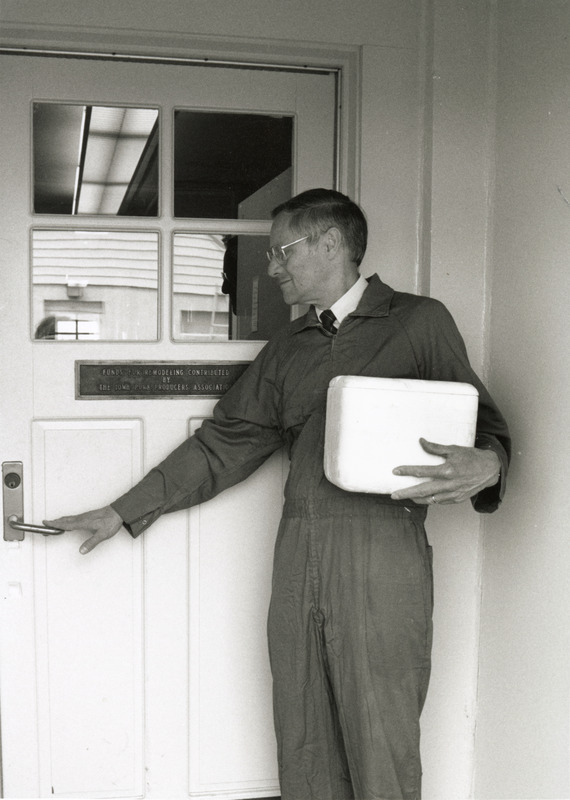 Photograph of Richard Ross entering a lab building with a cooler