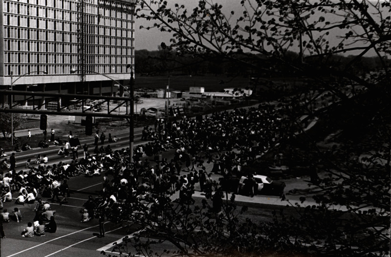 Photograph of a crowd of student anti-war protesters sitting on Lincoln Way in Campustown as part of a demonstration.