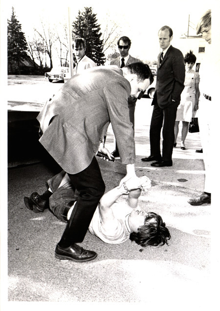 Photograph of a law enforcement officer tackling an anti-war protester during a Vietnam War protest near campus.