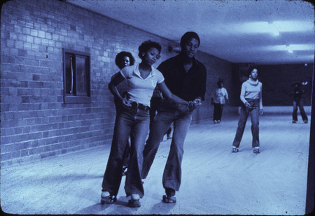 Photograph showing students roller skating at an event held by the Office of Minority Student Affairs at Iowa State University.